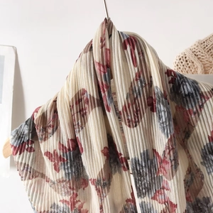 Detail of floral pleated scarf with fine texture hanging on a wooden hanger