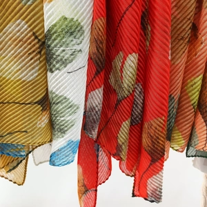 Detail of pleated summer shawl with artistic ginkgo leaf prints in vibrant colors