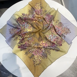 Gros plan d'un foulard carré en coton fleuri avec bords roulés sur marbre