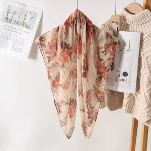 Detail of pleated floral scarf featuring orange roses on a cream textured fabric