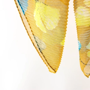 Detailed view of yellow ginkgo leaf print scarf with pleated texture and light fabric