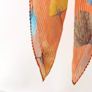 Detailed macro view of pleated fabric with orange and blue ginkgo leaf prints