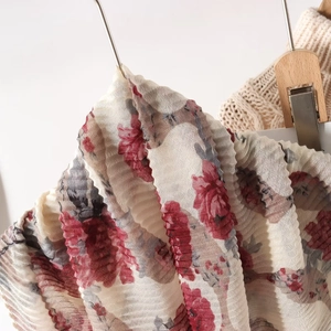 Close-up of pleated floral scarf with red blossoms on lightweight breathable fabric