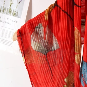 Detail of red floral plissé scarf featuring ginkgo print and crinkle texture fabric