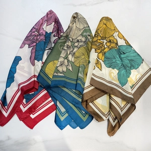 Three elegant silk-like scarves featuring floral and dragonfly prints on marble surface