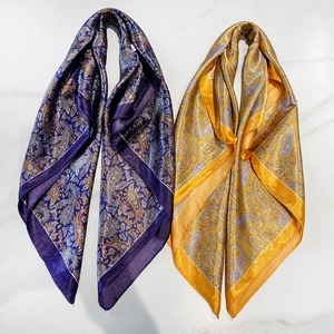 Dettaglio di foulard in seta satinata con motivi paisley su sfondo di marmo