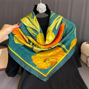 Floral print large silk square scarf in deep green and yellow displayed on a hanger