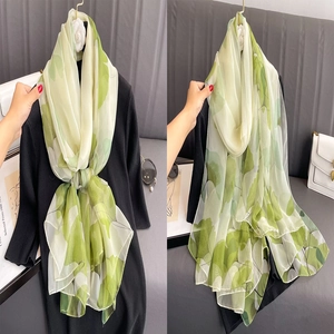 Lightweight long scarf with green floral print shown tied and draped for summer styling