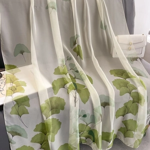 Lightweight long scarf with green ginkgo leaf print displayed on a stylish handbag