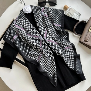 Elegant green houndstooth silk scarf with purple accents styled on a black sweater