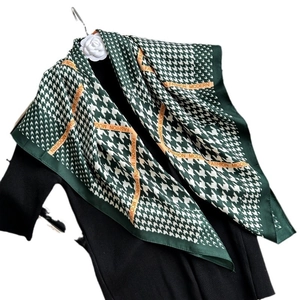 Green houndstooth silk scarf with orange fashion trim draped on a black top