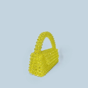 Detail of handmade yellow acrylic beaded flap trapezoid handbag on blue background