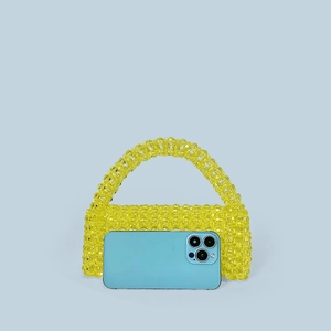 Detail of yellow beaded acrylic handbag with a blue smartphone to show actual size scale