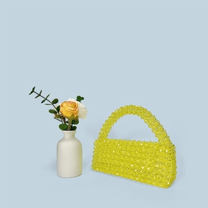 Detailed close-up of yellow beaded acrylic handbag texture and handcrafted woven pattern