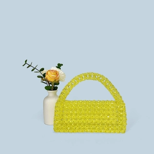Detail of yellow handmade beaded handbag featuring transparent acrylic beads and woven texture