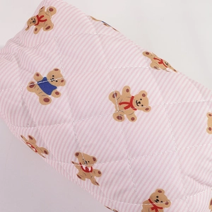 Gros plan sur le tissu matelassé à rayures roses avec motifs ours et surpiqûres fines