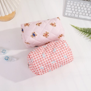 Trousses de maquillage en coton matelassé avec motifs ours et nœuds sur bureau blanc