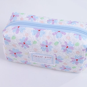 Close-up of floral quilted pencil case with textured fabric and Sweet Girl woven label