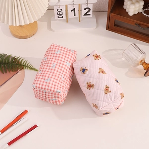 Détail de pochettes matelassées aux motifs ours et nœuds sur un bureau chaleureux