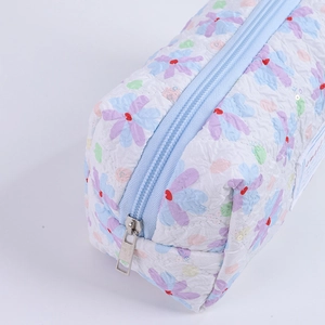 Detailed macro view of floral quilted fabric texture and blue zipper closure on pen bag