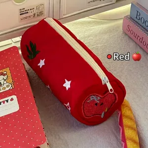 Red canvas pencil case with star patterns and apple embroidery on desk
