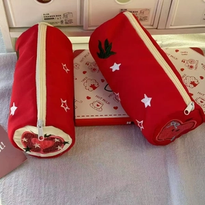 Detail of red cylindrical pencil case with white star and strawberry heart embroidery