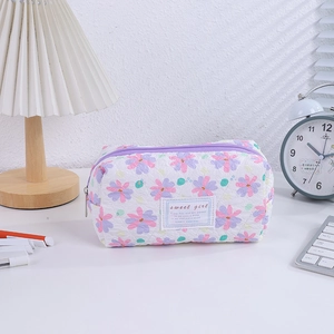 Detail of floral quilted pencil case with sweet girl label and purple zipper on desk