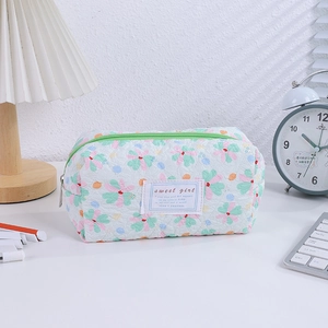 Quilted floral pencil case with green zipper shown in a cozy desk setting