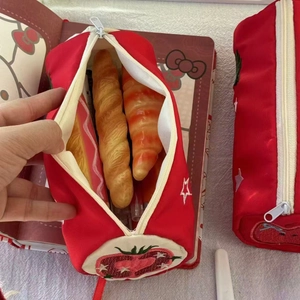 Detail of red canvas pencil case with fruit embroidery and realistic bread-shaped pens