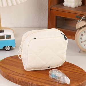Dettaglio della trousse bianca trapuntata con stampe di cartoni animati e cerniera tonda