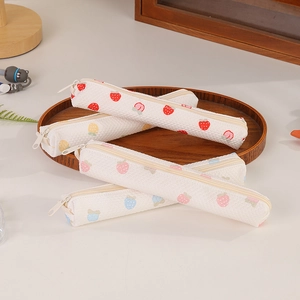 Close-up of four aesthetic strawberry print fabric pencil cases in a wooden tray