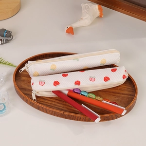 Detailed close-up of quilted strawberry and fruit pattern pencil cases on a wooden tray