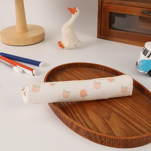Detail of waffle fabric pencil case with peach patterns on a wooden tray