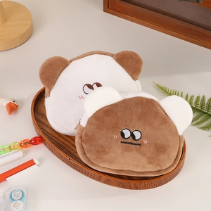 Detail of plush bear coin pouches with embroidered facial expressions on wooden tray