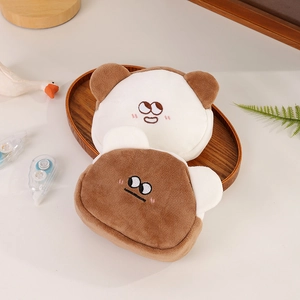 Close-up of cute plush bear coin purses with embroidered faces on a wooden tray