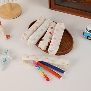 Detail of waffle fabric pencil case with fruit prints and zip closure on wooden desk