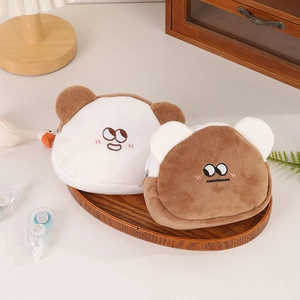 Detail of plush bear mini pouches with embroidery and zipper on an oval wooden tray