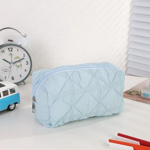 Detail of light blue quilted nylon pencil case with diamond pattern and zipper