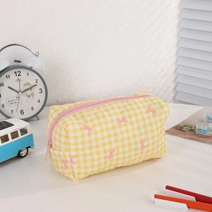 Detailed view of yellow checkered quilted pencil case with cute pink bows and zipper