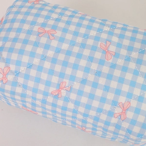 Macro shot of blue gingham quilted pencil case with pink ribbon bow pattern texture