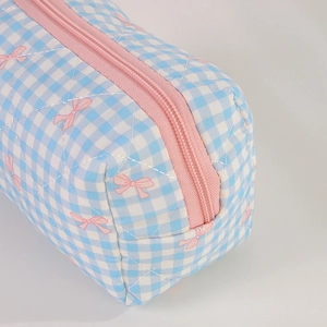 Close-up of quilted blue gingham pencil case with pink bow print and metal zipper