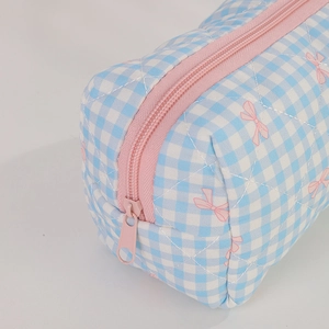 Close-up of quilted blue gingham pencil case with pink bow prints and a sturdy zipper