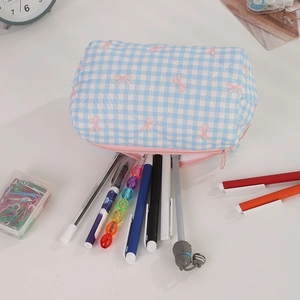 Quilted blue gingham pencil case with pink bows and multiple pens inside on a desk