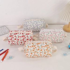 Detailed view of four floral quilted pen cases with zipper closures and side handles