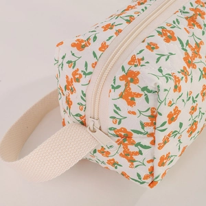 Detailed close-up of quilted cotton floral bag with orange blossoms and cream zipper