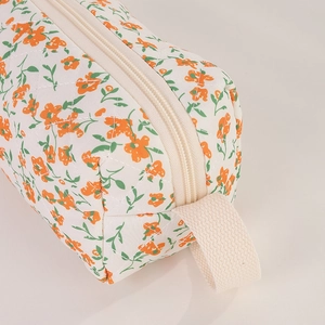 Detail of quilted gardenia floral makeup bag with white zipper and fabric handle