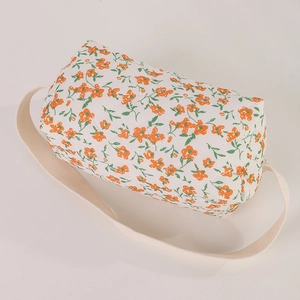 Close-up of cylindrical quilted storage bag with orange floral pattern and cotton strap