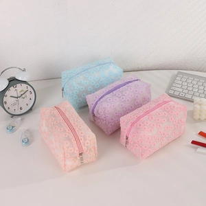 Detailed view of four mesh makeup bags with floral applique in pink, purple, blue, and orange