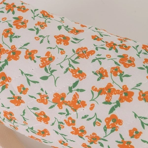 Macro detail of quilted floral fabric with orange flowers and green leaves on stationary bag