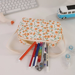 Close-up of floral quilted fabric pencil case with orange blossoms and side handle